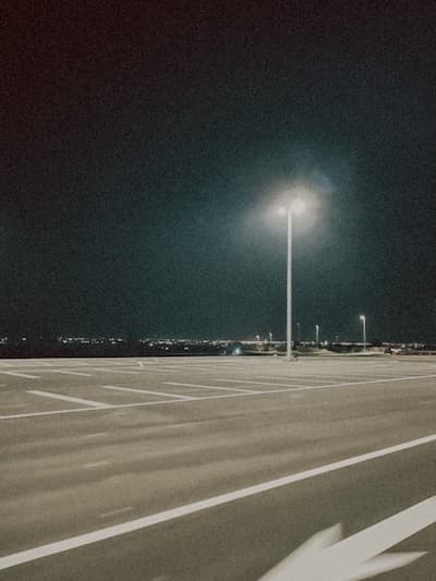 Empty Parking Area with a single streetlight with lights in the far distance.